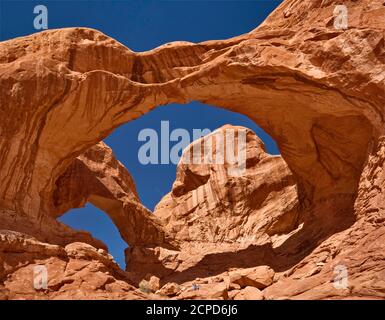 Escursionisti seduti sotto il Double Arch, Arches National Park, Utah, USA Foto Stock