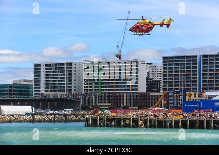 Il Westpac Rescue Helicopter ha effettuato un salvataggio simulato nel porto di Auckland, Nuova Zelanda, guardato da una folla sui moli. Gennaio 26 2019 Foto Stock