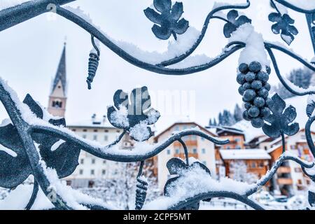 paesaggio invernale nelle dolomiti, il villaggio di pieve di livinallongo visto attraverso una porta in ferro battuto, livinallongo del col di lana / buchenstein, campana Foto Stock