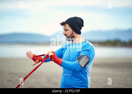 Ragazzo giovane che si prepara per un addestramento di boxe su una spiaggia con un bel tempo Foto Stock