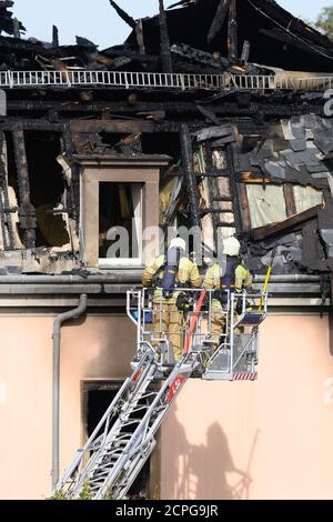 Dresda, Germania. 19 Settembre 2020. I vigili del fuoco ispezionano il traliccio del tetto da una scala giradischi dopo un incendio in un edificio di appartamenti. Si dice che il fuoco sia iniziato in un appartamento al secondo piano e poi si è allargato alla capriata del tetto attraverso il controsoffitto. Un uomo ha cercato di salvarsi dal fuoco saltando fuori dalla finestra della casa il sabato mattina. Gli è stato immediatamente dato cure mediche di emergenza e portato in un ospedale. Non ci sono state altre lesioni. Credit: Sebastian Kahnert/dpa-Zentralbild/dpa/Alamy Live News Foto Stock
