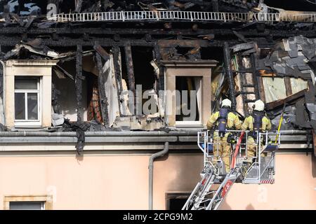 Dresda, Germania. 19 Settembre 2020. I vigili del fuoco ispezionano il traliccio del tetto da una scala giradischi dopo un incendio in un edificio di appartamenti. Si dice che il fuoco sia iniziato in un appartamento al secondo piano e poi si è allargato alla capriata del tetto attraverso il controsoffitto. Un uomo ha cercato di salvarsi dal fuoco saltando fuori dalla finestra della casa il sabato mattina. Gli è stato immediatamente dato cure mediche di emergenza e portato in un ospedale. Non ci sono state altre lesioni. Credit: Sebastian Kahnert/dpa-Zentralbild/dpa/Alamy Live News Foto Stock