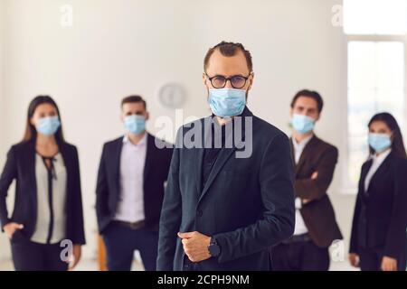 Giovane azienda leader con gruppo di lavoratori responsabili indossare viso maschere sul posto di lavoro Foto Stock