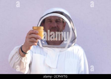 L'apicoltore tiene in mano un vaso di miele Foto Stock