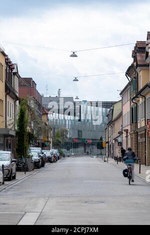 Germania, Baviera, Erlangen, strada vuota alla stazione ferroviaria principale, un ciclista. Foto Stock