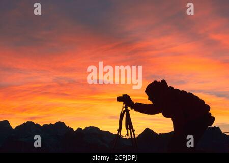 Silhouette di fotografo che scatta foto in montagna al tramonto, Dolomiti Foto Stock