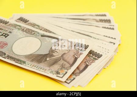 Diecimila yen (10,000 yen) banconote accatastate. Denaro giapponese. Carta denaro. Isolato su sfondo giallo. Vista dall'alto. Foto Stock