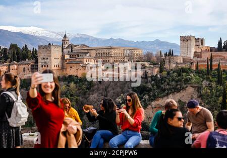 I turisti scattano foto con il castello moresco Alhambra, i palazzi Nasrid, il Palazzo Karl V., la Sierra Nevada coperta di neve sul retro, Granada, Foto Stock