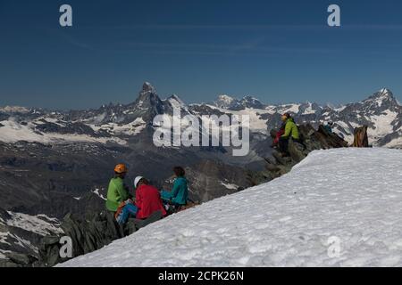 Svizzera, Cantone Vallese, Valle Saas, Saas-Fee, alpinisti in cima al riposo sul Alalinhorn con Cervino, Dent d'Herens, Monte Bianco, G. Foto Stock