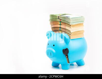 Banca piggy con pila di banconote in euro e chiave di casa auto isolato su sfondo bianco. Concetto di idea di successo finanziario. Trasporti immobiliari Foto Stock