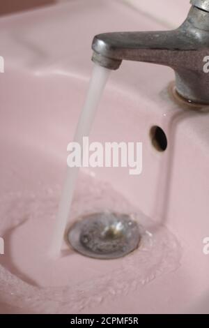 acqua che scorre dal rubinetto in bagno Foto Stock