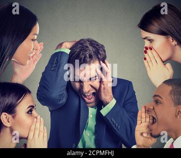 Gruppo di persone a bisbigliare una disperata ha sottolineato il business man Foto Stock