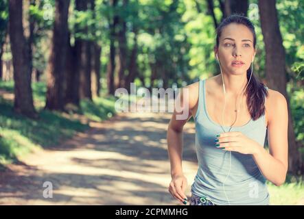 Giovane donna che corre in campagna indossando auricolari Foto Stock