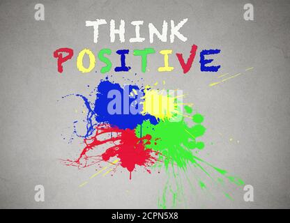 Verde, blu, rosso, giallo spruzzi di vernice isolato sfondo grigio parete, nero banner con spruzzi colorati pensano parole positive scrittura su di esso. Foto Stock