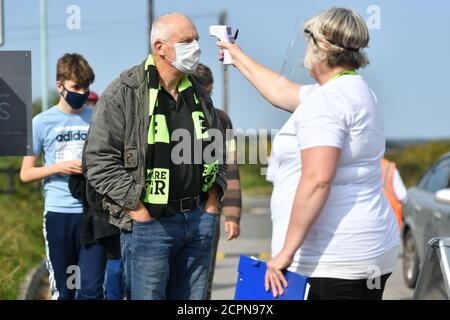 Un amministratore in PPE prova la temperatura di un fan durante la partita Sky Bet League due al New Lawn, Nailsworth. Foto Stock