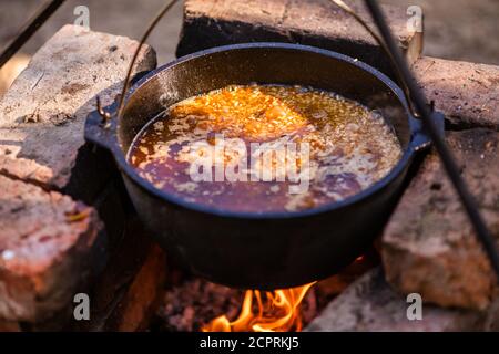 Preparazione di pilaf in un calderone su un fuoco aperto. Foto Stock