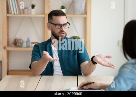 Cliente insoddisfatto giovane uomo che indossa occhiali che discutono con il manager Foto Stock