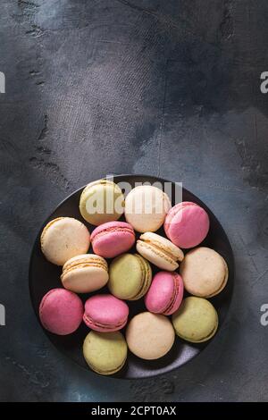 Piastra completa di vari macaron sul tavolo con spazio per la copia, vista dall'alto Foto Stock