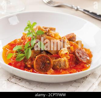 Piatto di maiale preparato con pomodoro, aglio e olio d'oliva. Servito con salsiccia chorizo. Foto Stock