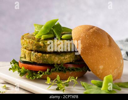 Hamburger vegano con fagioli verdi e ceci, servito con pomodoro, cetriolo e lattuga. Foto Stock