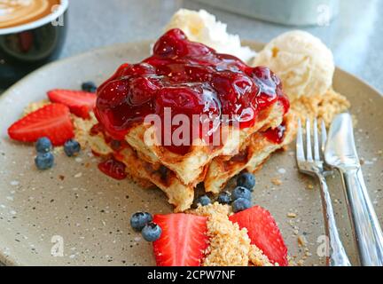 Piatto di appetitoso waffle con salsa di fragole, frutti di bosco freschi e gelato alla vaniglia Foto Stock