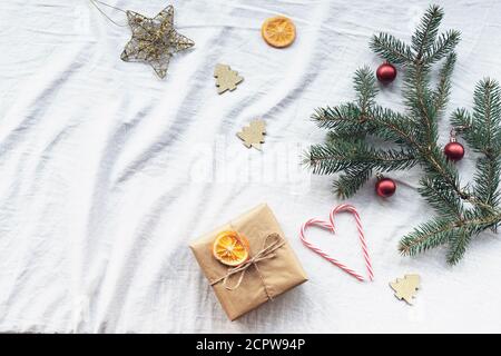 Layout di Capodanno con confezione regalo, rami di abete, decorazioni natalizie, caramelle bastone, arance secche. Vista dall'alto, disposizione piatta, spazio per la copia. Foto Stock