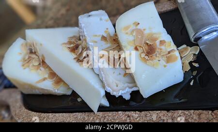 Primo piano del piatto di formaggio. Tavole di legno e marmo con vari tipi di formaggio e mandorle su un tavolo di legno. Foto Stock