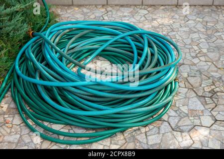 Un tubo flessibile da giardino piegato a spirale si trova sul massa Foto Stock