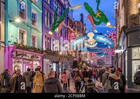 Folle di persone che camminano lungo Carnaby Street Londra con le luci di Natale a tema Ocean in testa, Londra, Regno Unito Foto Stock