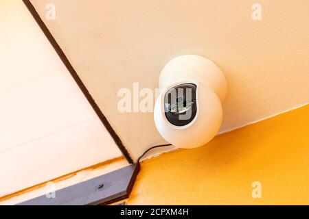 Telecamera TVCC bianca di sicurezza fuori casa. Telecamera di sorveglianza installata a soffitto per monitorare la protezione della casa. Foto Stock