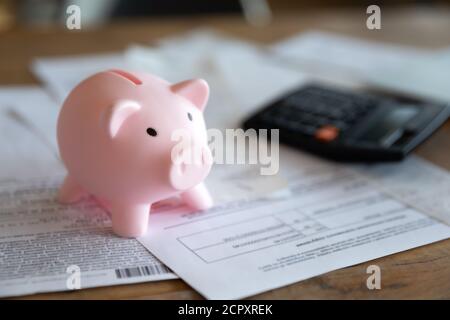 Primo piano della banca dei piggy con i documenti finanziari sul tavolo Foto Stock