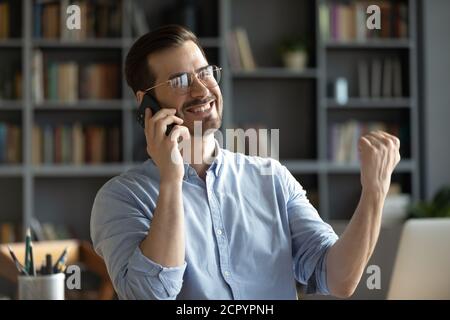 L'uomo eccitato si sente euforico avendo buone notizie sul cellulare Foto Stock