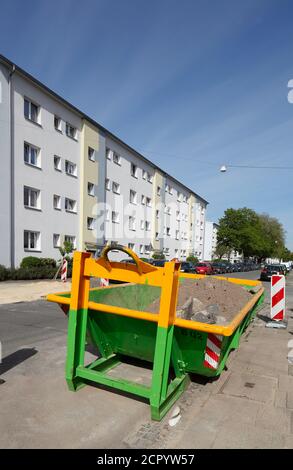 Contenitori di rifiuti per la costruzione di macerie in piedi sulla strada di fronte a monotoni edifici residenziali bianchi, Brema, Germania, Europa Foto Stock