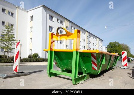 Contenitori di rifiuti per la costruzione di macerie in piedi sulla strada di fronte a monotoni edifici residenziali bianchi, Brema, Germania, Europa Foto Stock