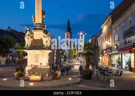 Atmosfera serale sulla piazza principale con la colonna mariana e il giardino degli ospiti, dietro la chiesa parrocchiale (S. Jakobuskirche), Leibnitz, Stiria, Austria Foto Stock