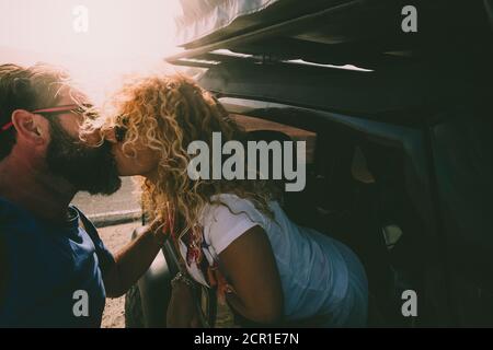 Una coppia adulta in amore bacio fuori dall'auto e viaggia insieme - concetto di stile di vita libero e felice per le belle persone che viaggiano e che amano la vita Foto Stock