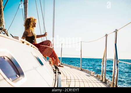 Giovane bella ragazza distendersi e rilassarsi su una barca a vela godendo di silenzio e natura - attività di svago estivo all'aperto durante le vacanze in yacth Foto Stock