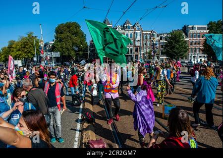 Gli attivisti sono visti ballare nel mezzo del ponte durante il rally.durante tutto il mese, il gruppo di attivisti del clima Extinction Rebellion nei Paesi Bassi ha pianificato una nuova campagna chiamata 'September Rebellion' per attirare l'attenzione sulla crisi climatica ed ecologica. Al Museumplein, ad Amsterdam, centinaia di attivisti della XR hanno danzato di chiedere un’azione contro il cambiamento climatico in quello che i manifestanti hanno definito "pubblico civile in discoteca". Gli attivisti hanno sventolato bandiere e ballato con canzoni come il successo del 1977 dei Bee Gees, Stayin’ Alive. Dopo la Museumplein gli attivisti si sono bloccati per pochi minuti uno dei più Foto Stock