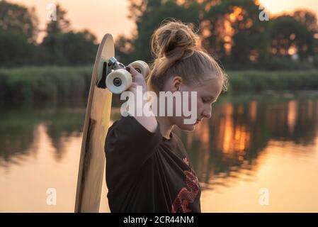 La ragazza si erge sul lago con un longbard al tramonto Foto Stock