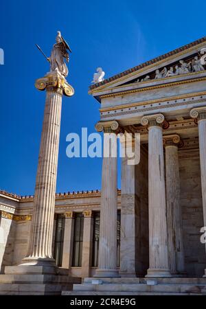 Colonna con la statua di Atena, antica dea greca, patrona della città, presso l'ingresso principale dell'Accademia di Atene, Grecia, il giorno d'estate a cielo blu Foto Stock