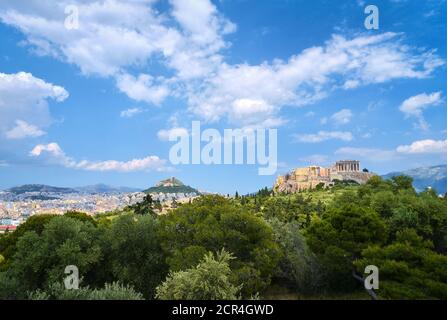 Vista iconica della collina dell'Acropoli e della collina di Lycabettus sullo sfondo di Atene, Grecia dalla collina di Pnyx nella luce del giorno d'estate con grandi nuvole nel cielo blu. Foto Stock