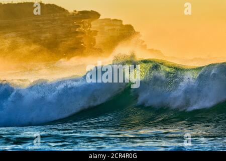 Ondulata e fluida onda smeraldo in una luce soffusa e luminosa al largo della spiaggia di Bronte a Sydney. Foto Stock