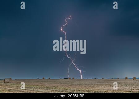 Temporale con fulmine su un campo stoppia in Turingia, Germania. Foto Stock