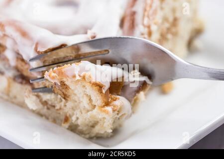 Utilizzando una forchetta per tagliare in un delizioso rotolo di cannella. Foto Stock