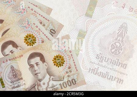 1000 bollette Thai Baht si trovano in pila sullo sfondo di una grande banconota semitrasparente. Background aziendale astratto con spazio di copia Foto Stock
