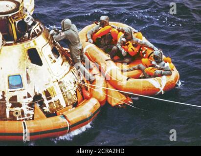 Pararescueman Lt. Clancy Hatleberg chiude l'Apollo 11 berlina veicolo spaziale come gli astronauti Neil Armstrong e Michael Collins e Buzz Aldrin, Jr., attendono di prelievo in elicottero dalla loro zattera di salvataggio. Essi spruzzato verso il basso a 12:50 pm EDT Luglio 24, 1969, 900 chilometri a sudovest di Hawaii dopo il successo di un atterraggio lunare di missione. Foto Stock