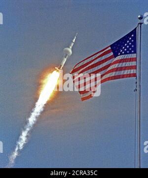 La bandiera americana araldi del volo di Apollo 11, il primo atterraggio lunare di missione. L'Apollo 11 Saturn V veicolo spaziale sollevata con gli astronauti Neil A. Armstrong, Michael Collins e Edwin E. Aldrin, Jr., a 9:32 a.m. EDT Luglio 16, 1969, dal Kennedy Space Center di complessi di lancio 39A. Foto Stock