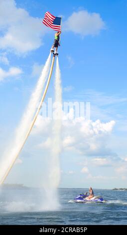 Rocket Man volare su una Jet Fly Board al lago Arlington, Texas e tenendo una bandiera americana. Foto Stock