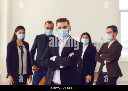 Il responsabile aziendale e i dipendenti si preoccupano dei clienti e dei colleghi che indossano maschere al lavoro Foto Stock