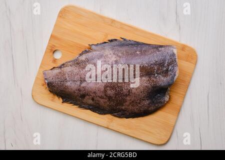 Vista dall'alto dell'halibut fresco grezzo senza testa in legno tagliere Foto Stock